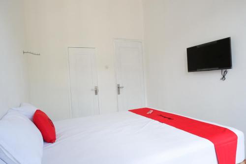 a white bed with red pillows and a tv on top at RedDoorz Plus near UMS Solo in Solo