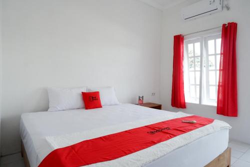 a bedroom with a large bed with red curtains at RedDoorz Plus near UMS Solo in Solo