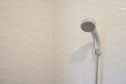 a shower with a shower head in a bathroom at RedDoorz Plus near UMS Solo in Solo