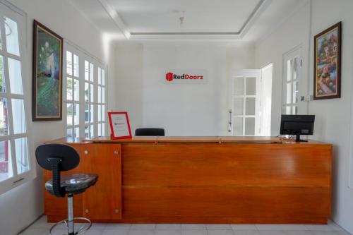 a wooden reception desk in a white room with windows at RedDoorz Plus near UMS Solo in Solo