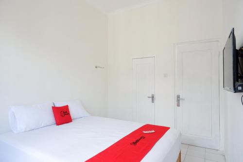 a bedroom with a white bed with a red blanket at RedDoorz Plus near UMS Solo in Solo
