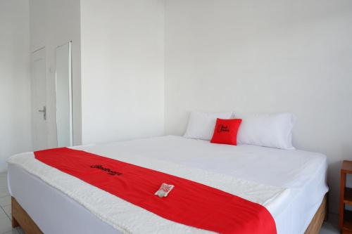 a white bed with a red blanket on it at RedDoorz Plus near UMS Solo in Solo