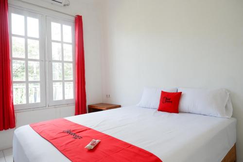 a bedroom with a large white bed with a red pillow at RedDoorz Plus near UMS Solo in Solo