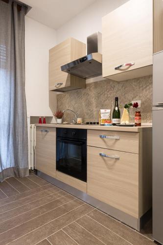 a kitchen with wooden cabinets and a stove at HH Hermoso Housing ALESSANDRIA in Alessandria