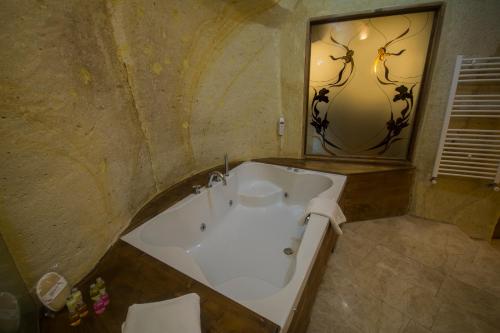 a bathroom with a tub and a large mirror at Fresco Cave Suites Cappadocia in Urgup