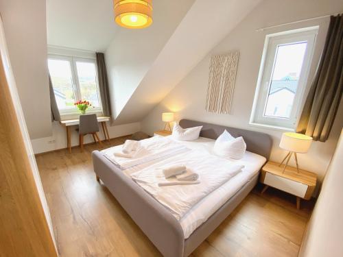 a bedroom with a white bed with two windows at mönchgut living & spa in Gager