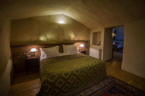 a bedroom with a bed with a green comforter and two lamps at Fresco Cave Suites Cappadocia in Urgup