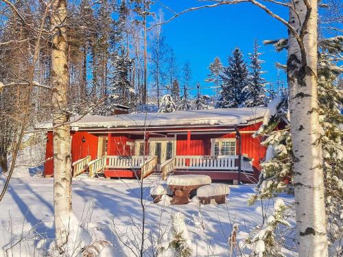 a red cabin in the snow in the woods at Holiday Home Juurlahti by Interhome in Hara