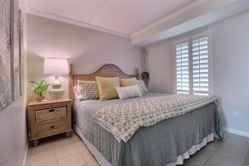 a bedroom with a bed and a lamp and a window at Island Winds East in Gulf Shores