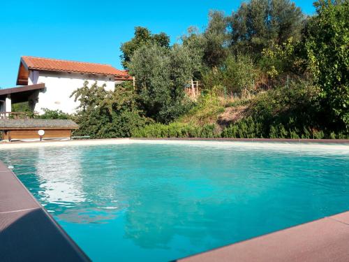 a swimming pool with blue water in front of a house at Apartment Casina - VDE211 by Interhome in Arnasco