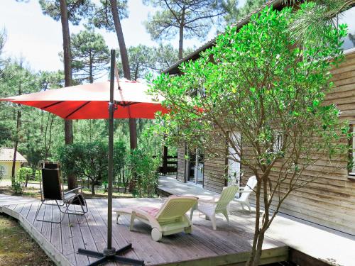 a patio with a red umbrella and chairs and a table at Chalet La Cigale - MAU190 by Interhome in Carcans