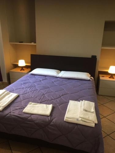 a purple bed with two towels on top of it at HH Hermoso Housing VALENZA in Valenza