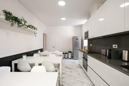 a kitchen with white chairs and a table and a counter at Home Out Rooms & Apartments in Lisbon