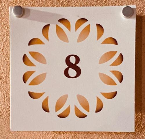 a white number eight sign on a wall at HH Hermoso Housing VALENZA in Valenza