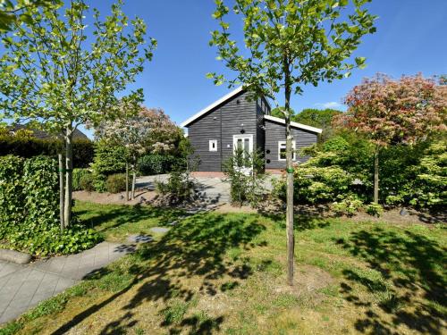 a black barn with trees in front of it at Holiday home with wifi in Eerbeek