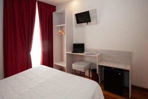 a bedroom with a bed and a desk with a television at Hotel Giardino in Bibbiena