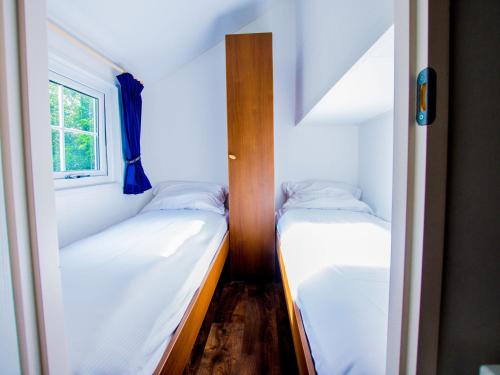 - 2 lits dans une petite chambre avec fenêtre dans l'établissement Cozy chalet with a dishwasher, in a holiday park in a natural environment, à IJhorst