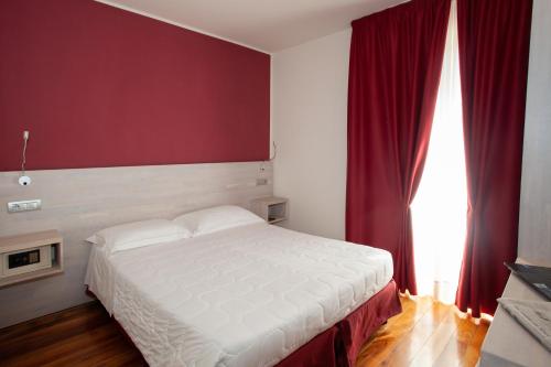 um quarto com uma cama branca e uma parede vermelha em Hotel Giardino em Bibbiena