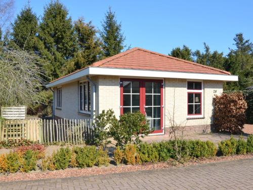 uma pequena casa branca com uma janela vermelha em Holiday home in the Veluwe in nature em Putten