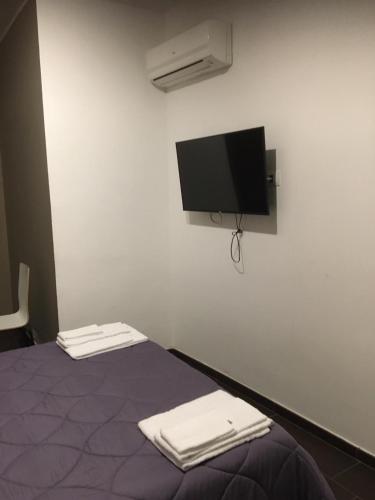 a room with a bed with a tv on the wall at HH Hermoso Housing VALENZA in Valenza