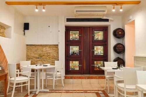 a restaurant with white tables and chairs and a wooden door at Hotel Rosa & Spa Begur in Begur