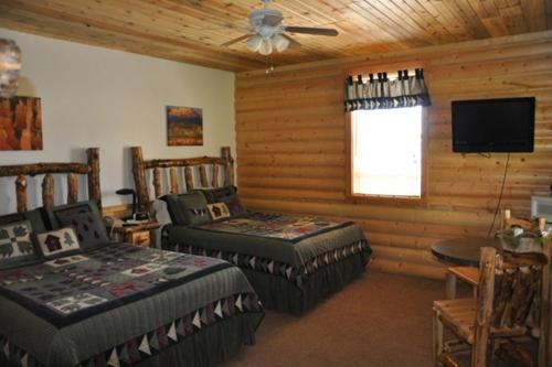 a bedroom with two beds and a television in a cabin at Bryce Country Cabins in Tropic