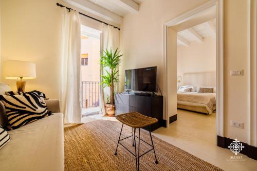 een woonkamer met een bank en een televisie bij Casa Ramal - Tipica dimora Siciliana in Siracusa
