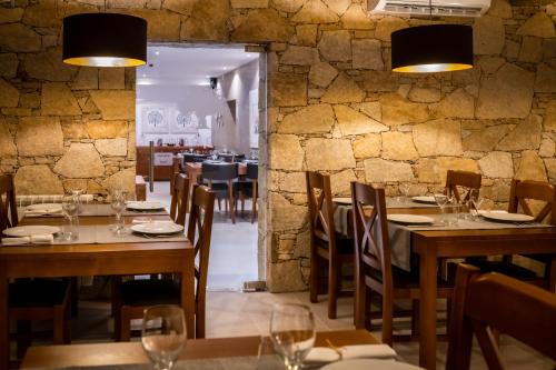 a restaurant with wooden tables and chairs and a stone wall at Quinta das Oliveiras Turismo Rural in Fundão