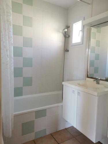 une salle de bain avec un lavabo, une baignoire et un miroir dans l'établissement Résidence le cordouan, à Soulac-sur-Mer