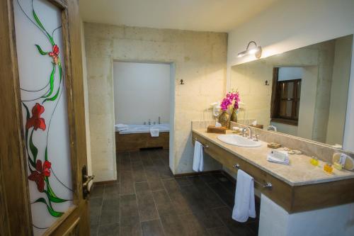 a bathroom with a sink and a large mirror at Fresco Cave Suites Cappadocia in Urgup