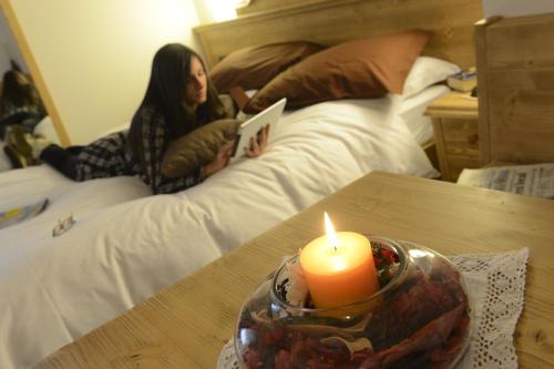 a woman laying on a bed reading a book with a candle at Hotel Vittoria in Folgaria