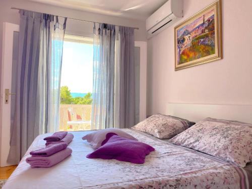 ein Schlafzimmer mit einem Bett mit lila Kissen darauf in der Unterkunft Guest House Meri in Bol