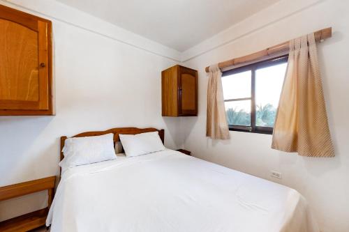 a bedroom with a white bed and a window at Way Suite @ Mayan Falls in Caye Caulker
