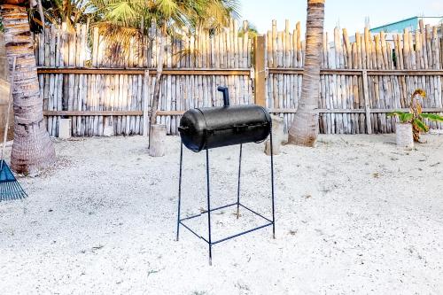 a black object sitting in the sand in front of a fence at Way Suite @ Mayan Falls in Caye Caulker