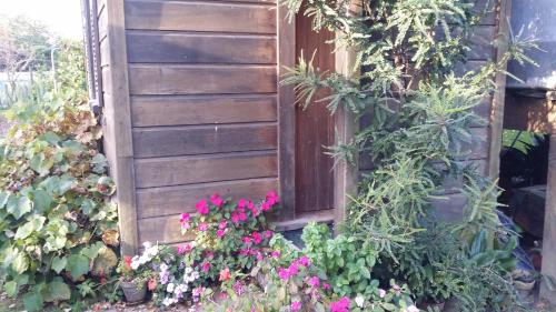 a garden with flowers and a wooden door at The Whare Rural Retreat in Hastings