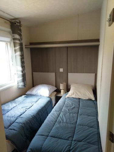 deux lits côte à côte dans une chambre dans l'établissement Bungalow familial avec piscine à Saint-Julien-en-Born, à Saint-Julien-en-Born