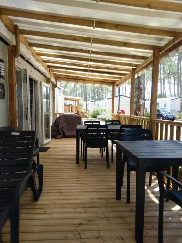 une terrasse couverte avec des tables et des chaises et un plafond en bois dans l'établissement Bungalow familial avec piscine à Saint-Julien-en-Born, à Saint-Julien-en-Born