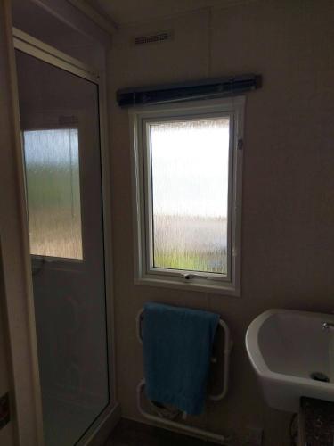 une salle de bain avec un lavabo et une fenêtre et une serviette dans l'établissement Bungalow familial avec piscine à Saint-Julien-en-Born, à Saint-Julien-en-Born