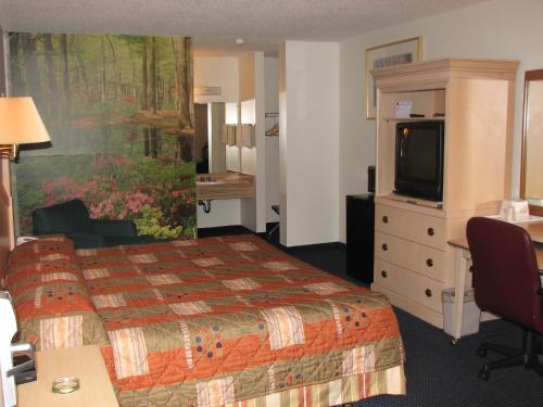 a hotel room with a bed and a television at Canterbury Inn & Suites in Parsons