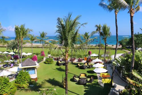 Holiday Inn Resort Baruna Bali, an IHG Hotel في كوتا: اطلالة جوية على منتجع فيه نخيل والمحيط