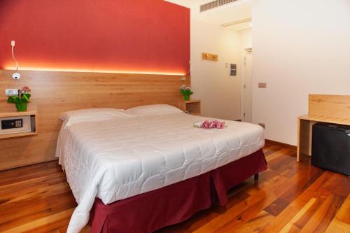 a bedroom with a large white bed with a red wall at Hotel Giardino in Bibbiena