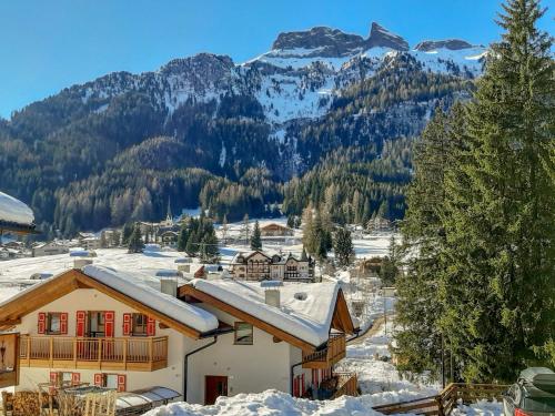 a house covered in snow with mountains in the background at Apartment Roacia-2 by Interhome in Alba di Canazei