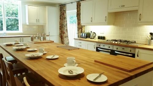 una cucina con tavolo in legno e piatti bianchi di East End House a Bury Saint Edmunds