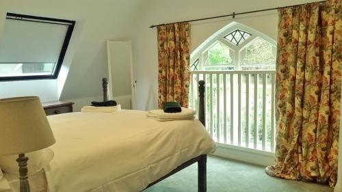 a bedroom with a bed and a large window at East End House in Bury Saint Edmunds