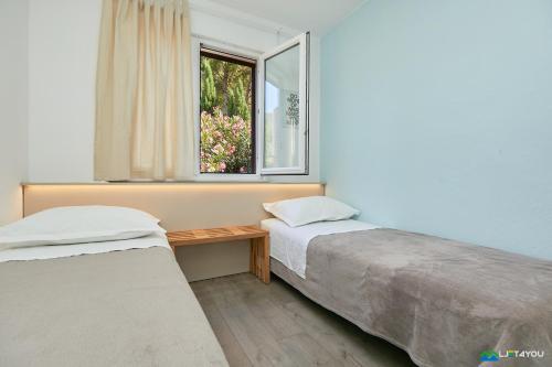 two beds in a room with a window at Mljet 4 You - seafront apartment in Sobra