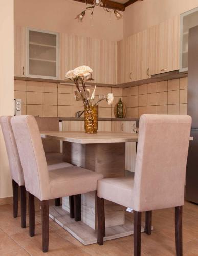 a dining room table with chairs and a vase with flowers at Soureto's House in Liapades