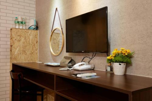 a desk with a phone and a television on a wall at At Tainan Inn in Tainan