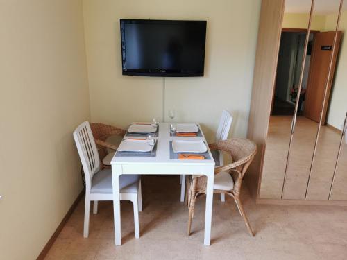 een witte tafel met stoelen en een televisie aan de muur bij Ferienwohnung und B&B Chasa Janett in Rudolfstetten