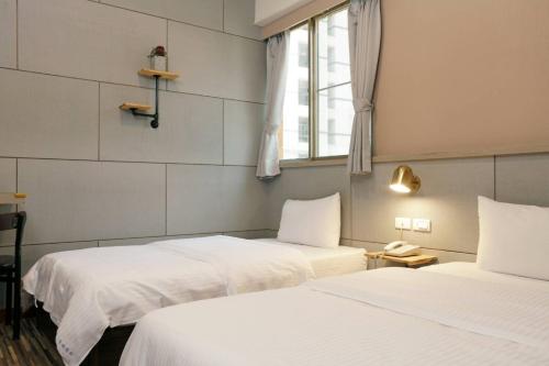a room with two beds and a window at At Tainan Inn in Tainan