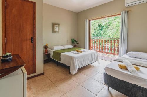 a bedroom with two beds and a large window at Pousada La Cabana in Itacaré